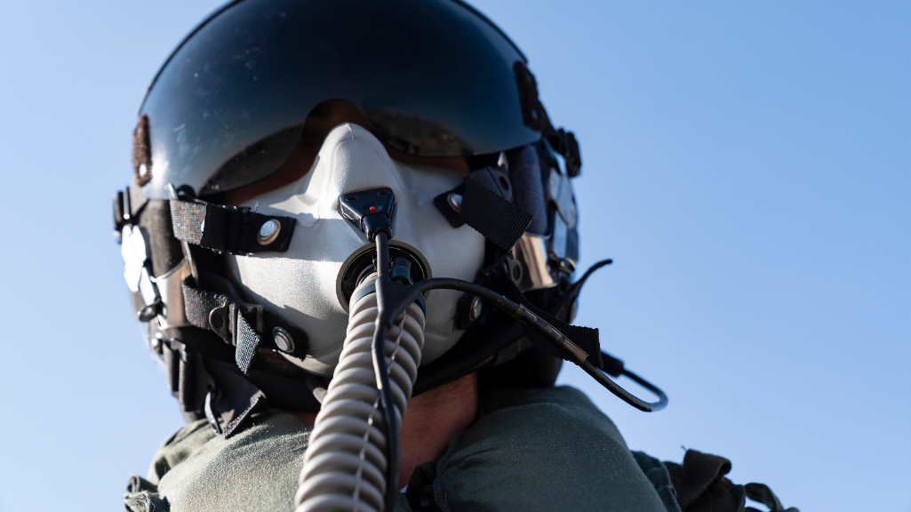 Fighter pilot wearing helmet and oxygen mask during high-G flight conditions demonstrating fighter pilot cervical training demands.