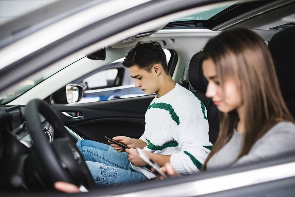 Two teens in a car using their phones, showing typical screen posture linked to tech neck - image provided by neckx