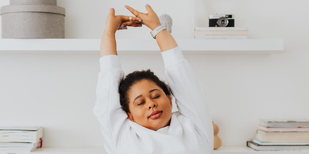 Woman stretching her neck at her desk during the workday.